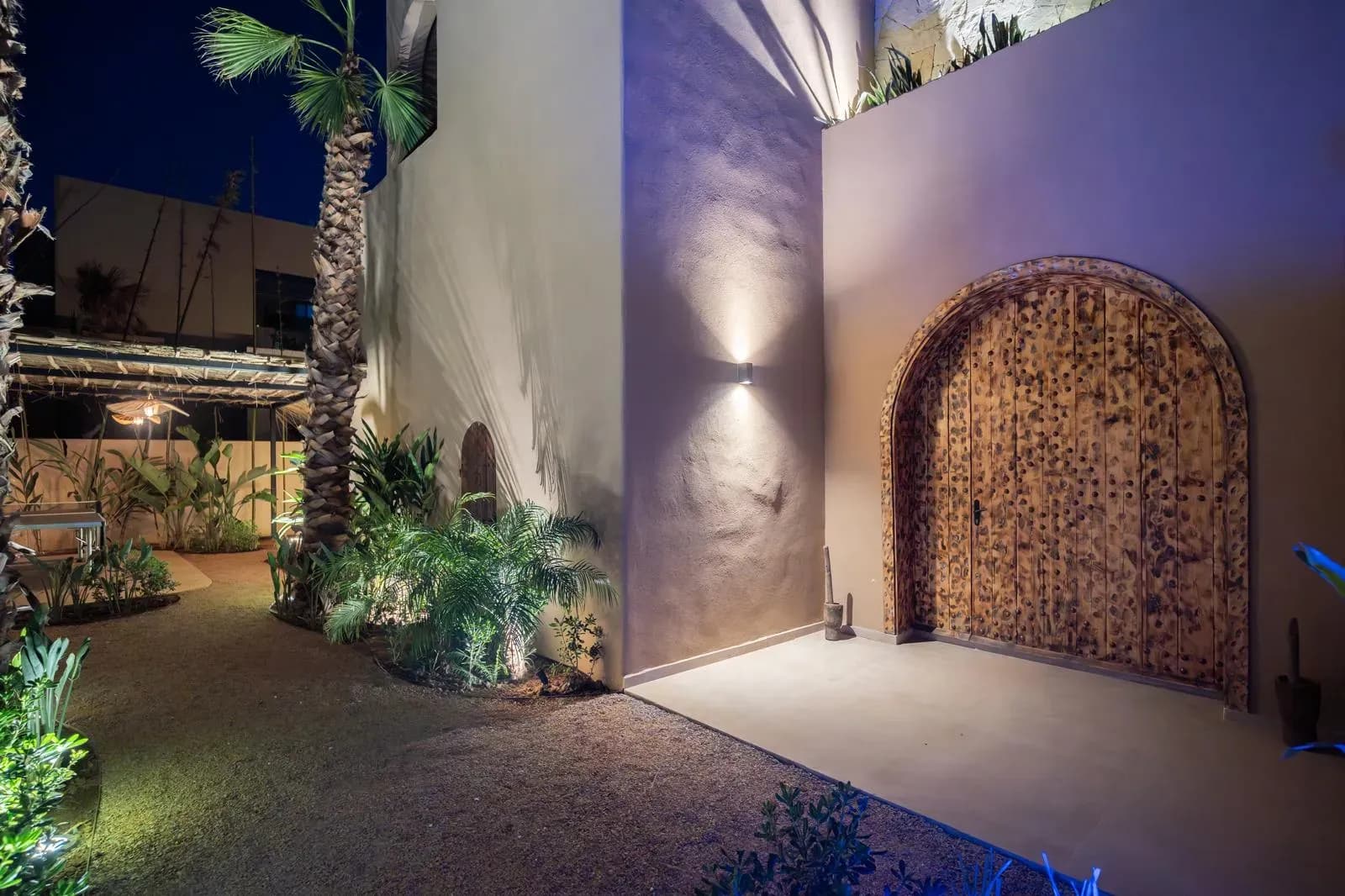 Villa Z, porte cintrée en bois dans un mur enduit éclairé de nuit